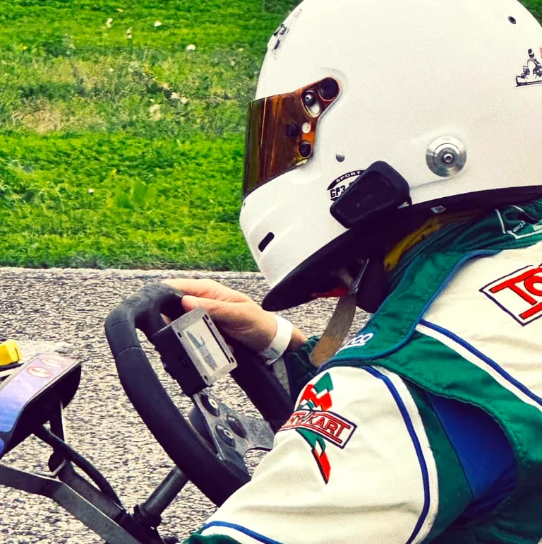Kart driver in helmet and racing suit with an ASTRO device mounted on the steering wheel
