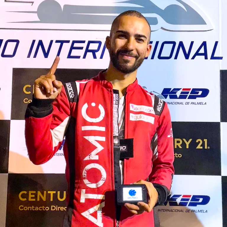 Driver on the podium holding an ASTRO device after a race win